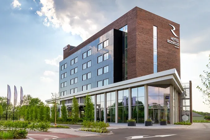 Moderne gevel van Hotel Rosveld met glaspartijen en bakstenen front onder een licht bewolkte lucht